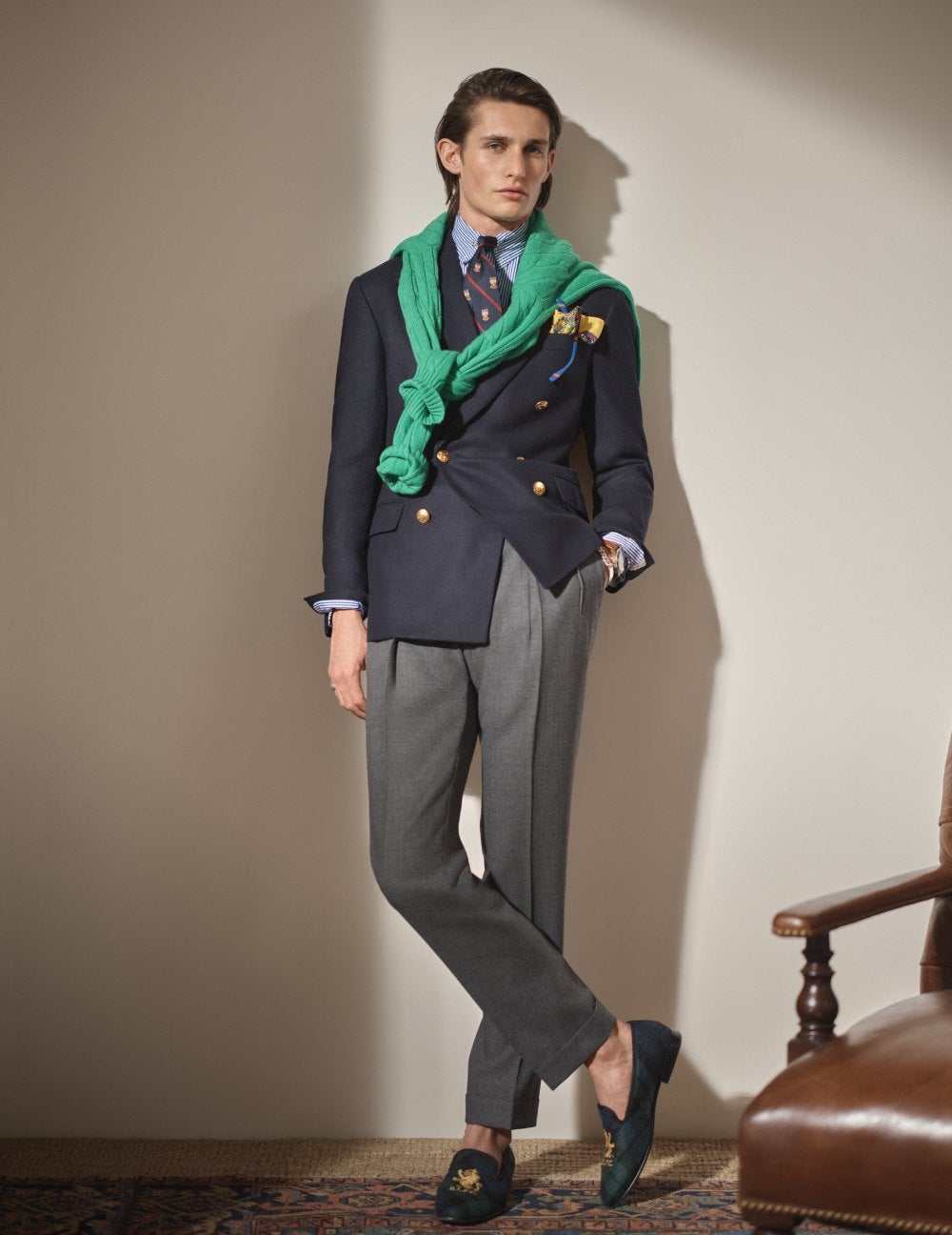 Man wears a navy blue double-breasted blazer and grey trousers.